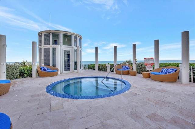 view of pool with a patio, a water view, and a hot tub