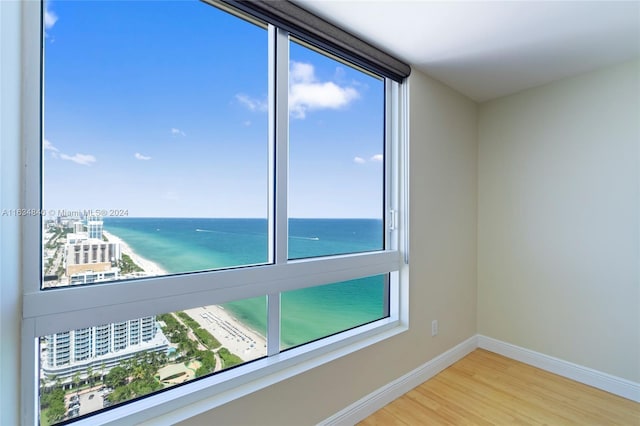 empty room with hardwood / wood-style floors, a water view, and a wealth of natural light