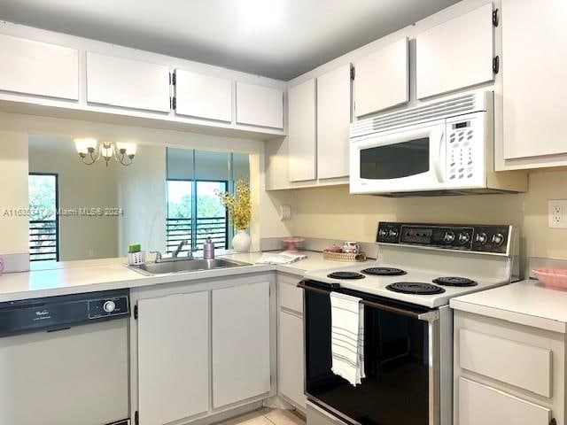 kitchen featuring sink, white cabinetry, a chandelier, and white appliances