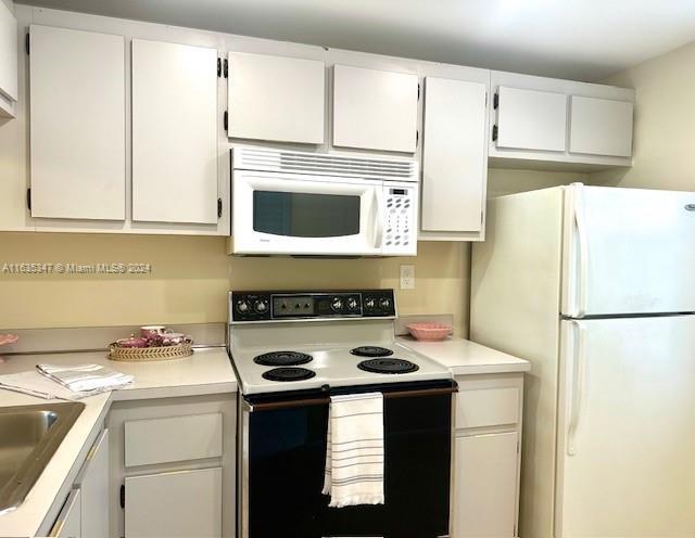 kitchen featuring sink, white appliances, and white cabinets