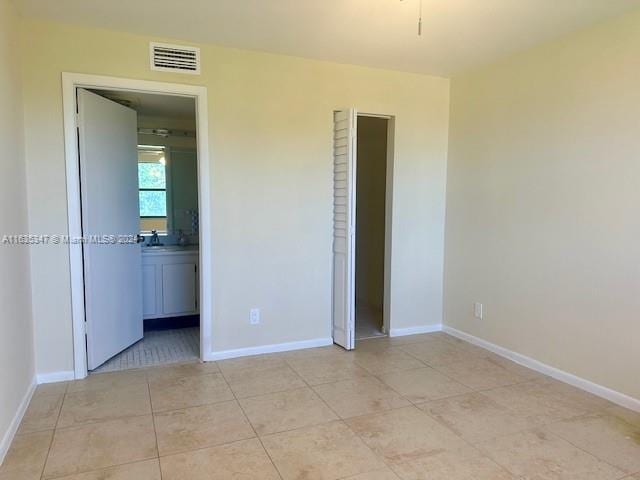 unfurnished bedroom featuring connected bathroom and light tile patterned floors