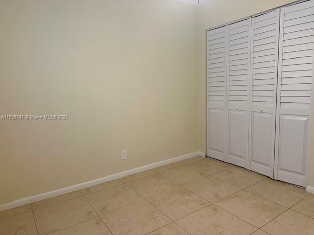 unfurnished bedroom featuring light tile patterned flooring and a closet