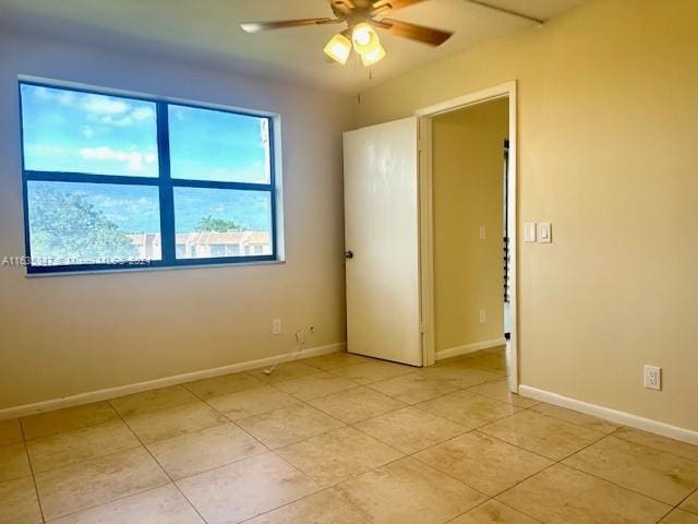 tiled empty room featuring ceiling fan