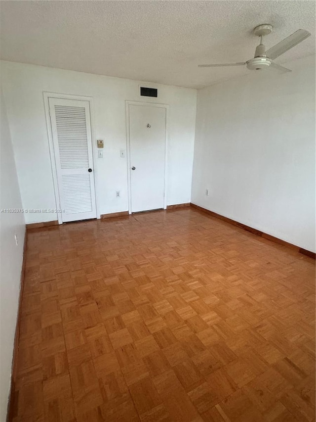 unfurnished room with a textured ceiling, parquet flooring, and ceiling fan