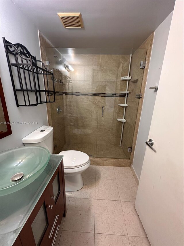 bathroom featuring tile patterned floors, toilet, walk in shower, and vanity