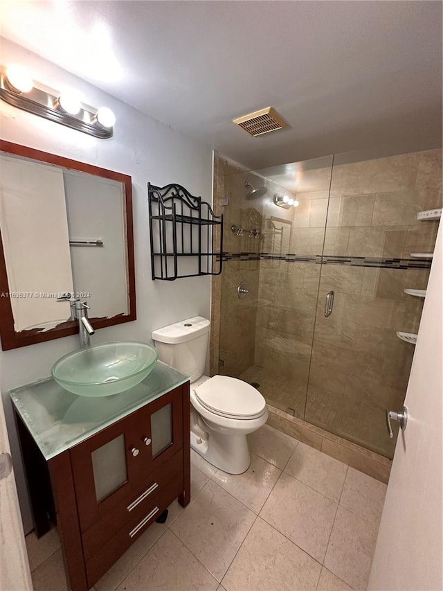 bathroom with an enclosed shower, toilet, vanity, and tile patterned floors