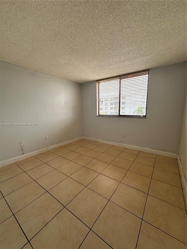 tiled spare room featuring a textured ceiling