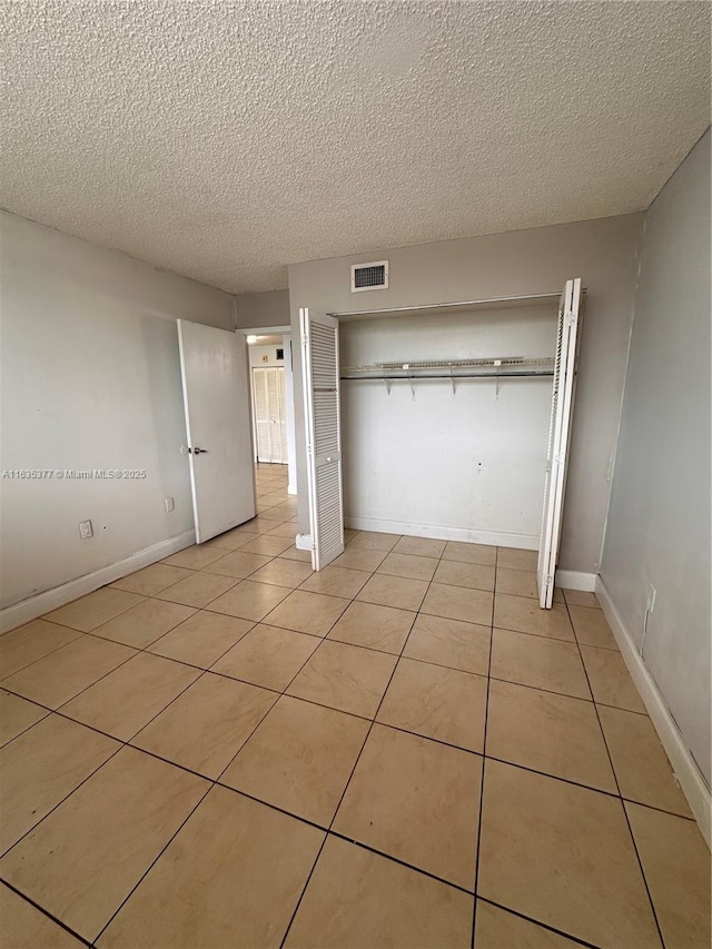 unfurnished bedroom featuring light tile patterned floors, a closet, visible vents, and baseboards