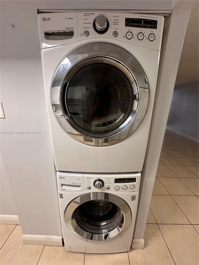 laundry area with stacked washer and dryer, baseboards, light tile patterned floors, and laundry area