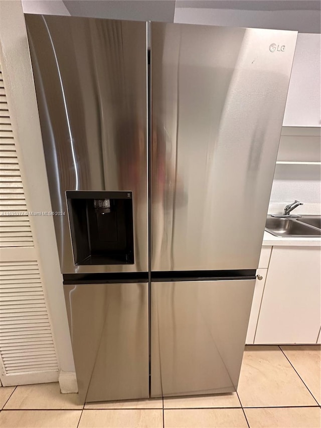 room details with light tile patterned floors, white cabinets, sink, and stainless steel refrigerator with ice dispenser