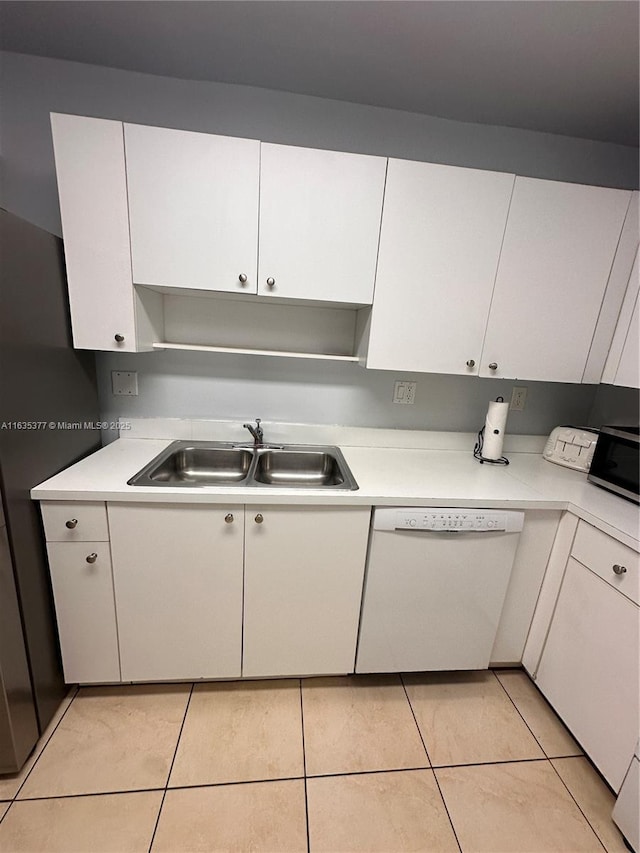 kitchen with white dishwasher, a sink, white cabinets, light countertops, and stainless steel microwave