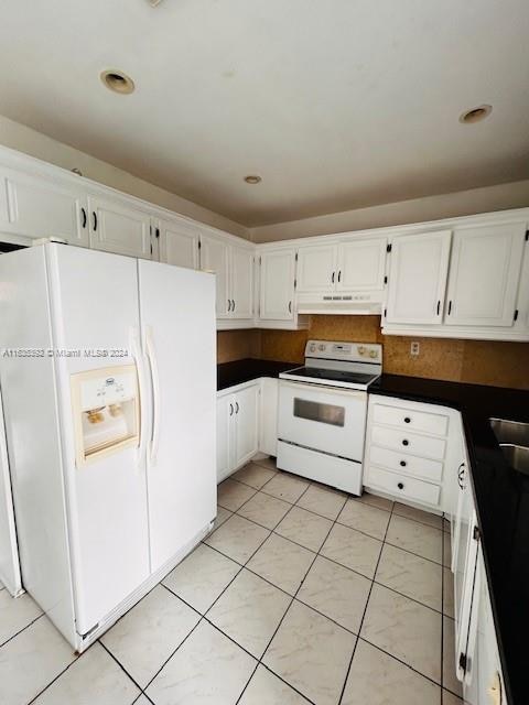 kitchen with white cabinets, light tile patterned flooring, and white appliances