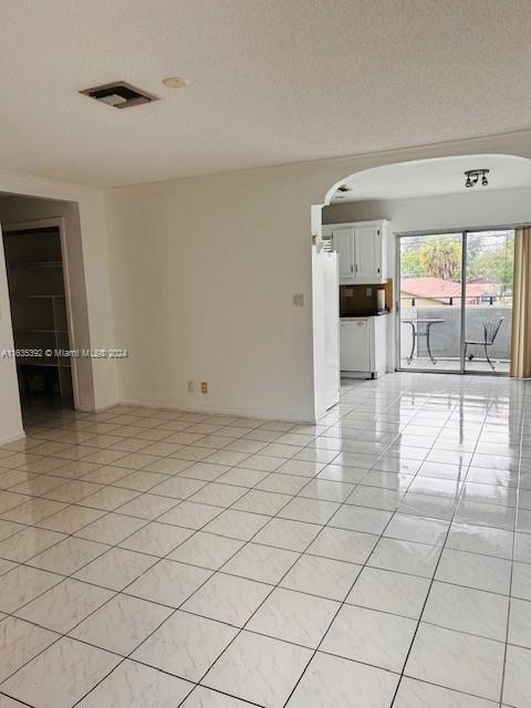 tiled empty room with a textured ceiling