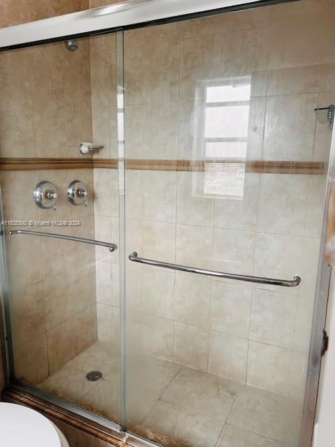 bathroom with a shower with door and toilet