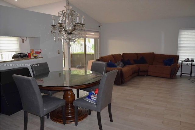 dining space with a notable chandelier, light wood-type flooring, and lofted ceiling