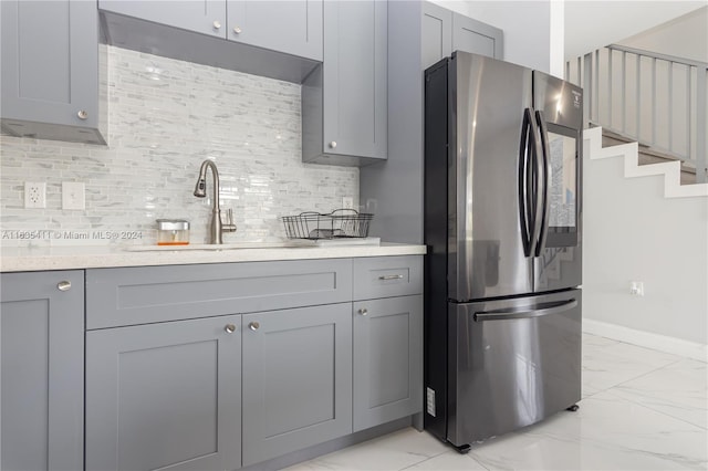 kitchen with gray cabinetry, light countertops, freestanding refrigerator, marble finish floor, and a sink