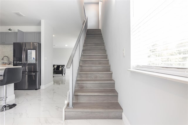 stairway with visible vents, marble finish floor, and baseboards