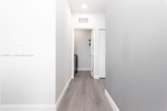 hall featuring visible vents, baseboards, and light wood-type flooring