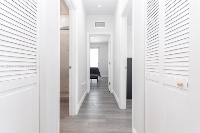 hallway with visible vents, baseboards, and wood finished floors