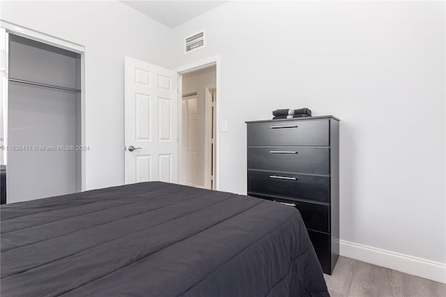 bedroom with visible vents, baseboards, a closet, and wood finished floors