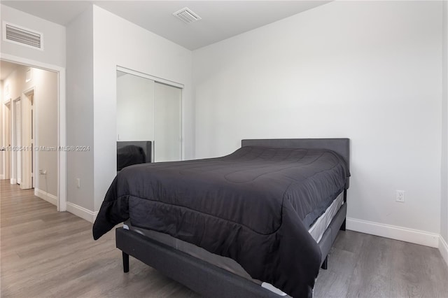 bedroom with visible vents, baseboards, light wood-style floors, and a closet