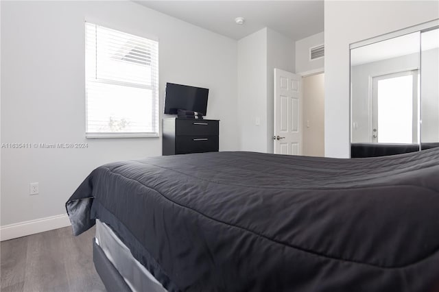 bedroom with visible vents, multiple windows, baseboards, and wood finished floors