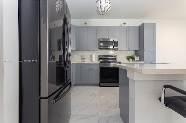 kitchen featuring gray cabinetry, marble finish floor, backsplash, and stainless steel appliances