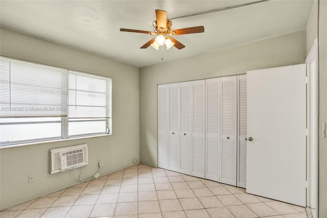 unfurnished bedroom with light tile patterned floors, ceiling fan, a closet, and a wall mounted AC