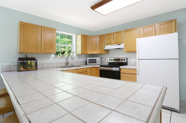 kitchen with tile countertops, white appliances, sink, light tile patterned floors, and light brown cabinetry