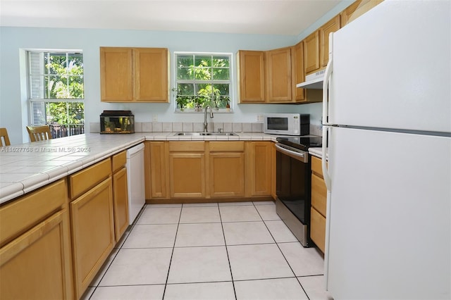 kitchen featuring tile countertops, light tile patterned flooring, white appliances, and sink