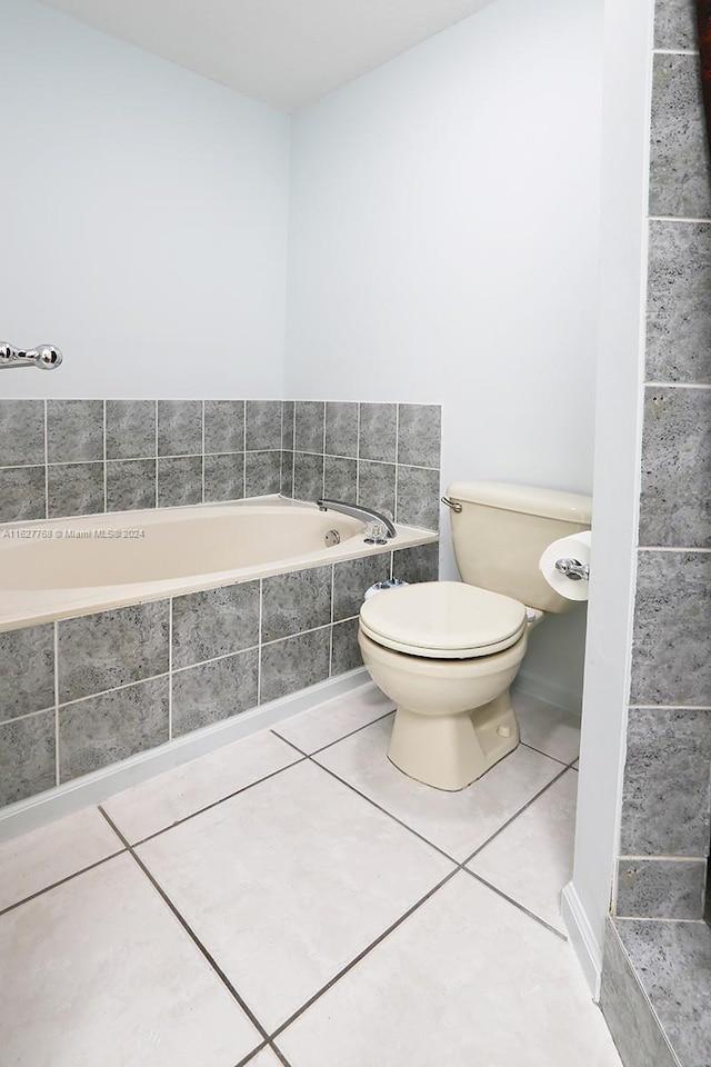 bathroom featuring tiled tub, tile patterned flooring, and toilet