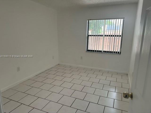 spare room with light tile patterned floors and a textured ceiling