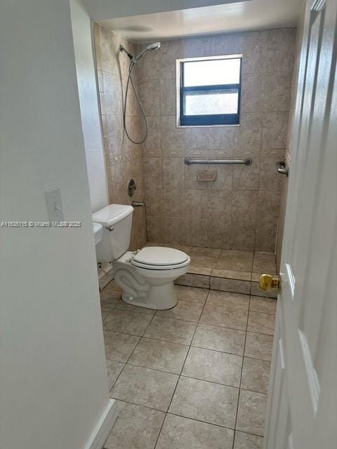 bathroom with a tile shower, tile patterned flooring, and toilet