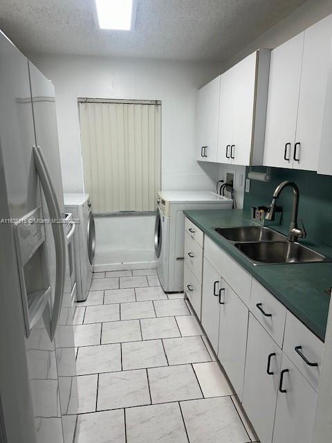 clothes washing area featuring cabinets, light tile patterned floors, sink, and washing machine and clothes dryer