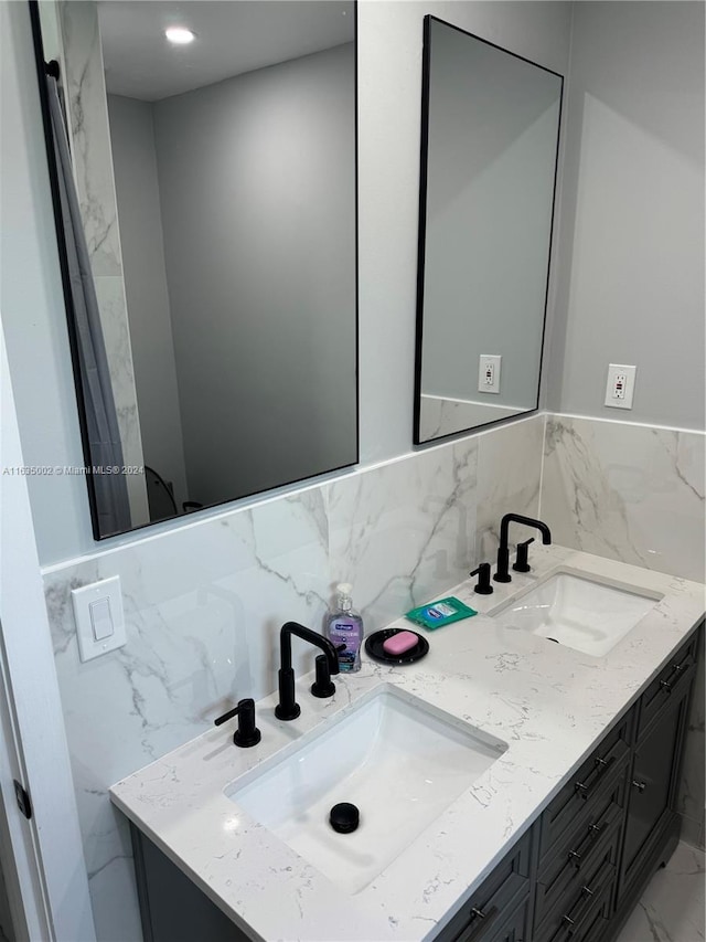 bathroom with decorative backsplash, tile walls, and dual bowl vanity