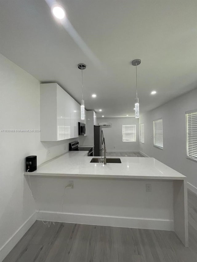 kitchen with pendant lighting, wood-type flooring, stainless steel appliances, and white cabinets