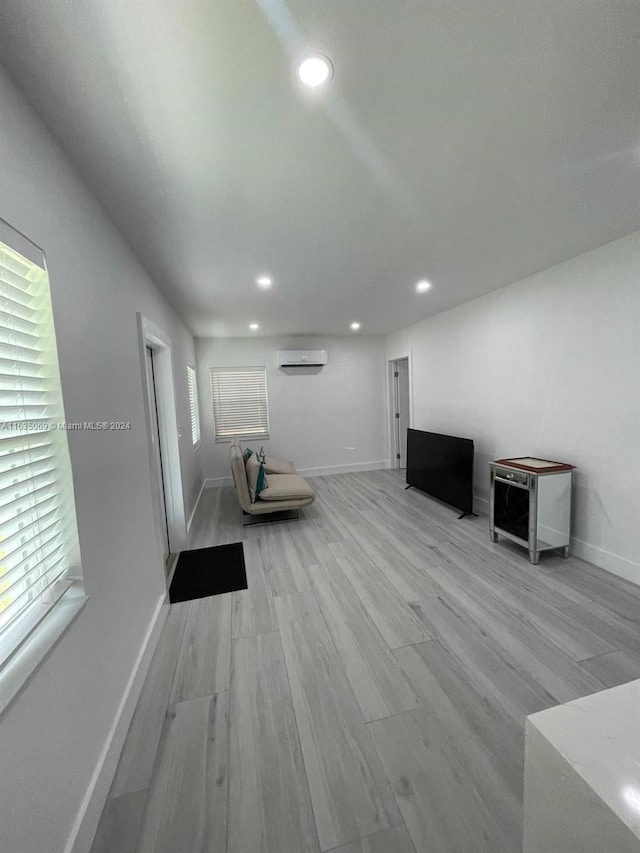 unfurnished living room featuring hardwood / wood-style flooring and a wall unit AC