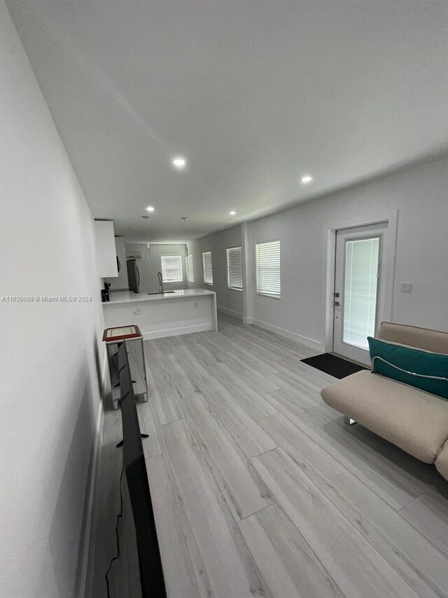 unfurnished living room featuring sink and light hardwood / wood-style floors