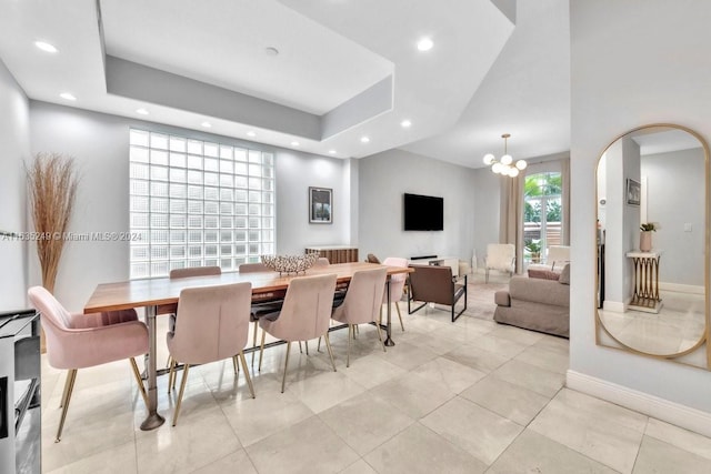 tiled dining area featuring a tray ceiling and an inviting chandelier