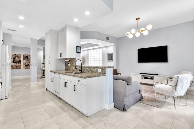 kitchen with hanging light fixtures, light stone counters, sink, and white cabinetry