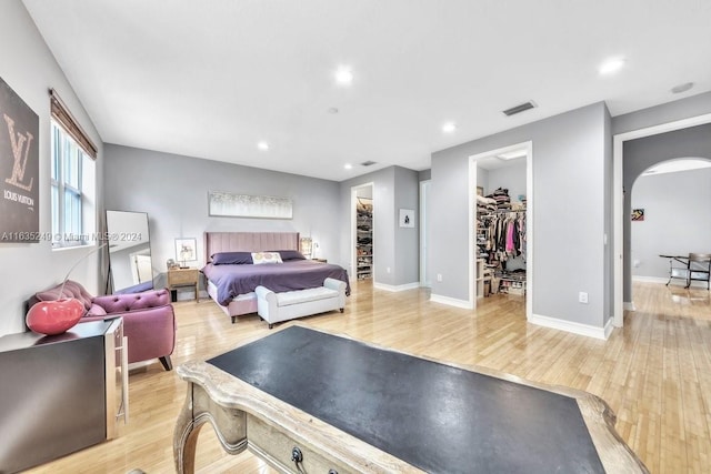 bedroom featuring light wood-type flooring, a walk in closet, and a closet