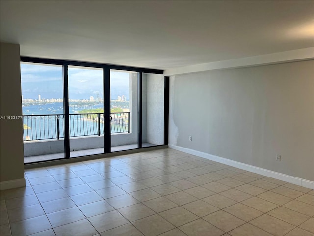 empty room with light tile patterned floors and a wall of windows