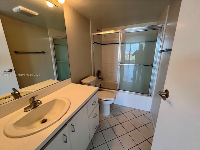 full bathroom featuring tile patterned flooring, bath / shower combo with glass door, toilet, and vanity