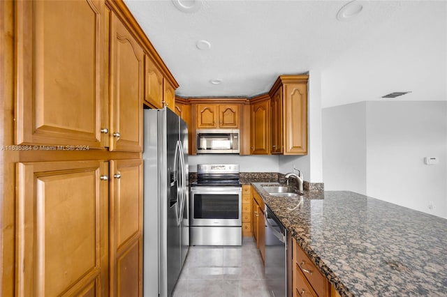 kitchen featuring dark stone countertops, appliances with stainless steel finishes, and sink