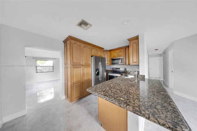 kitchen with dark stone countertops, sink, appliances with stainless steel finishes, and kitchen peninsula