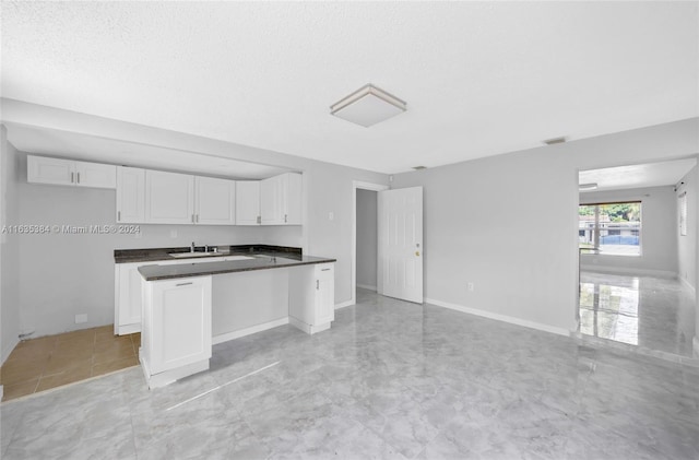 kitchen featuring white cabinets, a textured ceiling, and sink