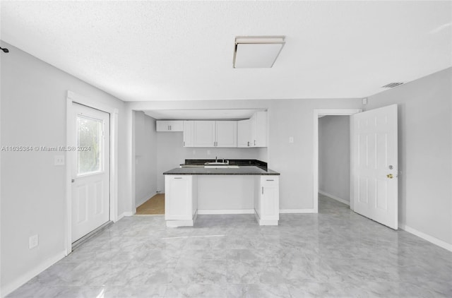 kitchen featuring a textured ceiling, sink, and white cabinetry