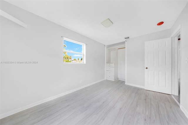 unfurnished bedroom with light wood-type flooring and a closet