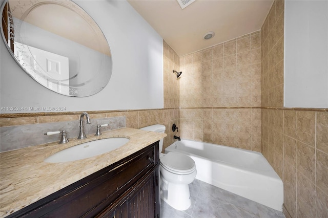 full bathroom with vanity, tile walls, tiled shower / bath combo, and toilet