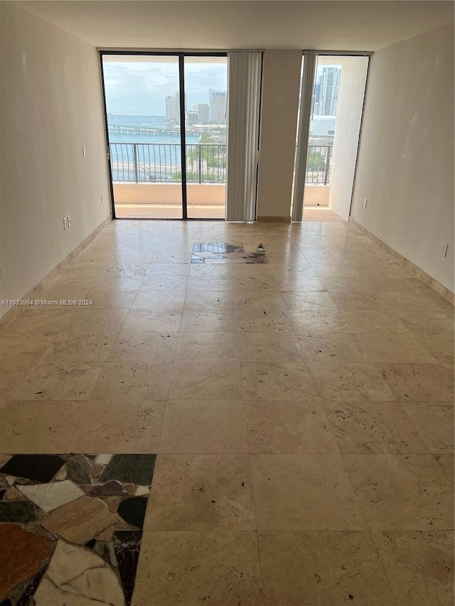 tiled empty room featuring floor to ceiling windows